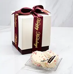 A white box with a red ribbon and a piece of cake.