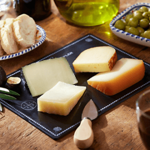 A plate of cheese and other food on the table.